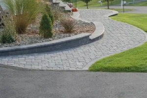 Curved paver walkway with raised edging and landscaping, showing durable hardscape walkway design installed by hardscaping contractors near Omaha, NE.