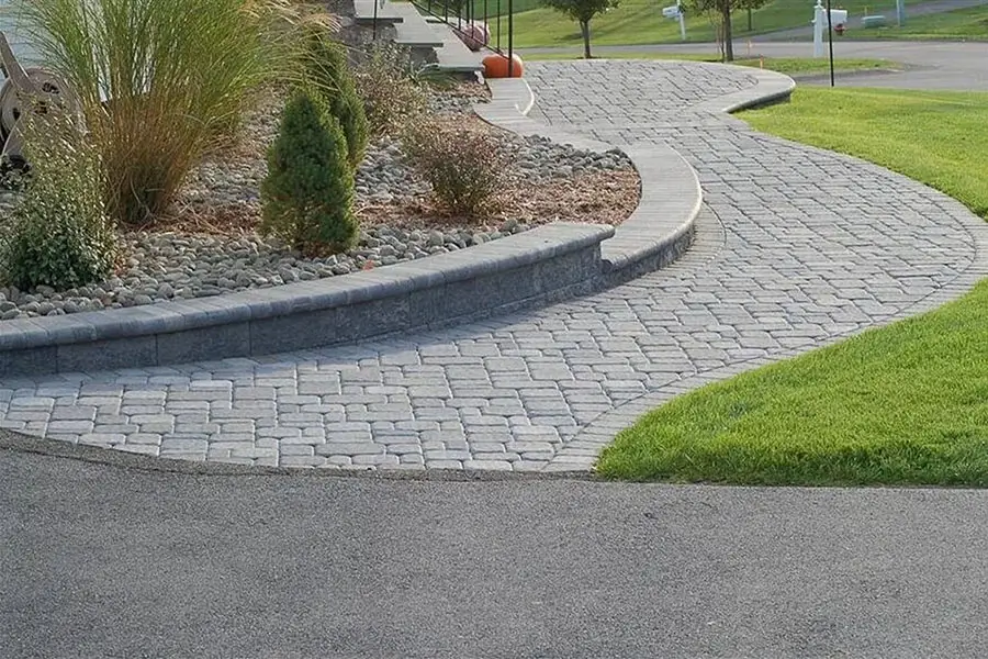Curved paver walkway with raised edging and landscaping, showing durable hardscape walkway design installed by hardscaping contractors near Omaha, NE.