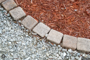 Wood mulch and decorative rock landscape beds separated by stone edging in an Omaha residential landscaping project.