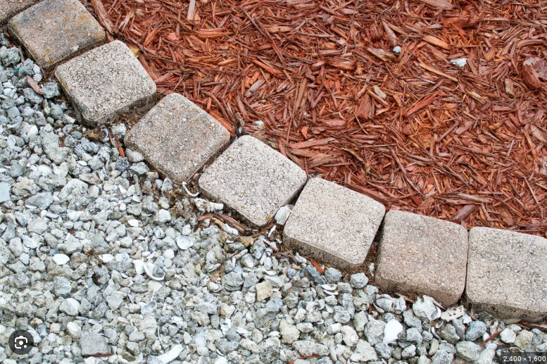 Wood mulch and decorative rock landscape beds separated by stone edging in an Omaha residential landscaping project.
