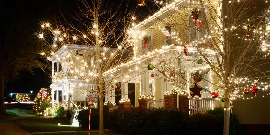 Beautifully decorated house with festive holiday lights and ornaments on trees, creating a warm Christmas atmosphere.